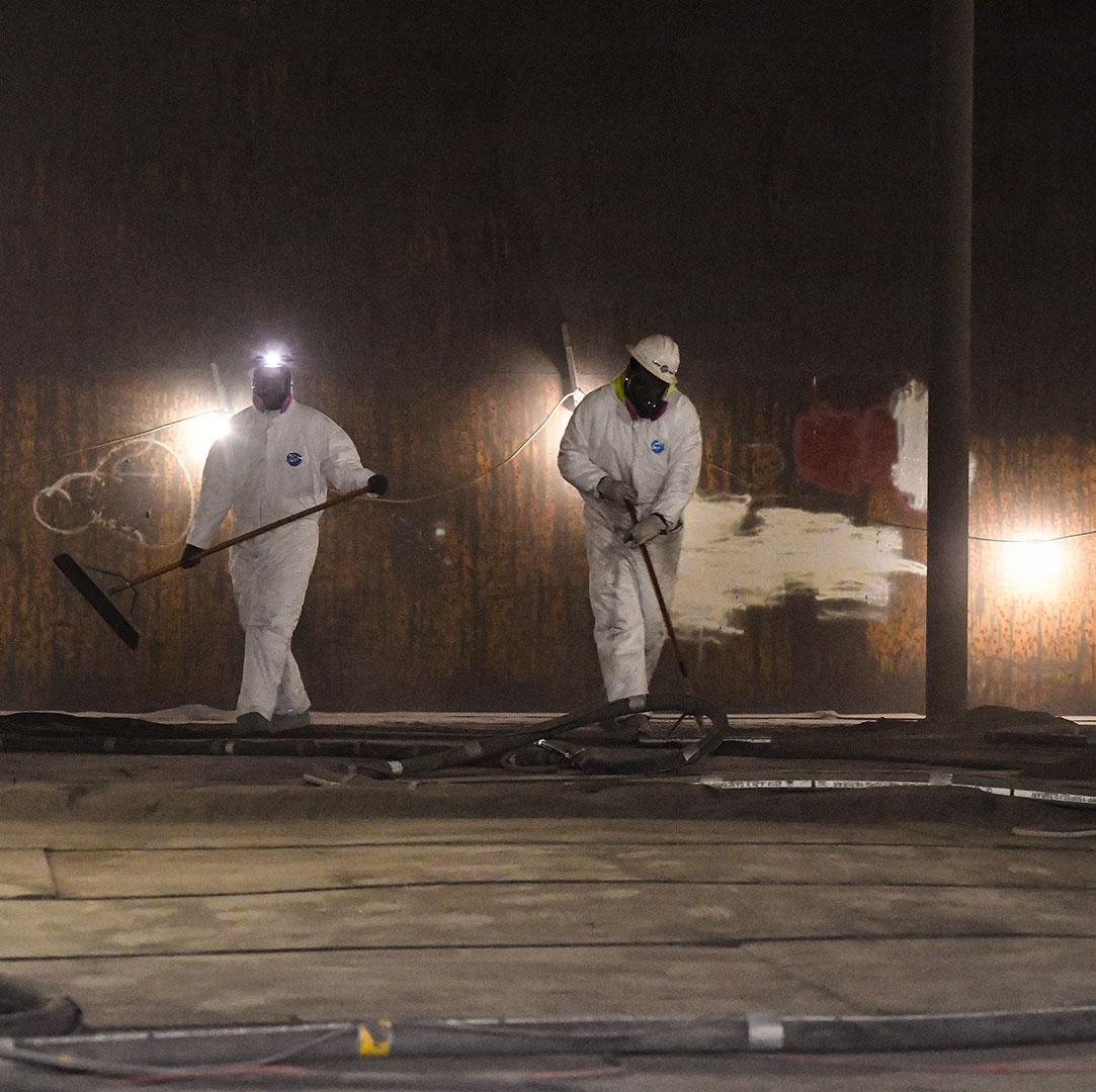 Image of two masked field crew workers cleaning the inside of a water tank