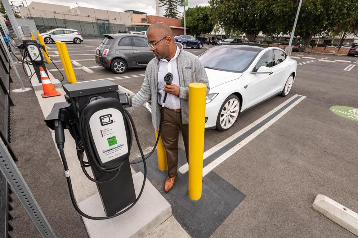 A man prepares to charge his electric vehicle in a parking lot