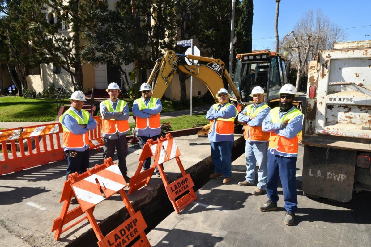 Construction crew standing in front of front of construction equipment