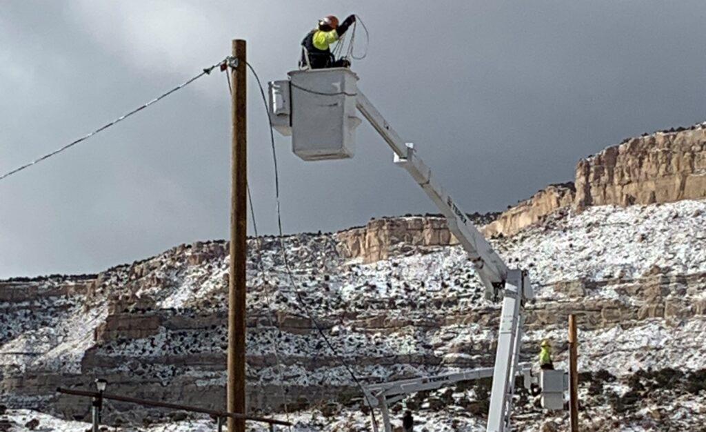 Image of a lineman in a cherry bucket connecting a transmission pole