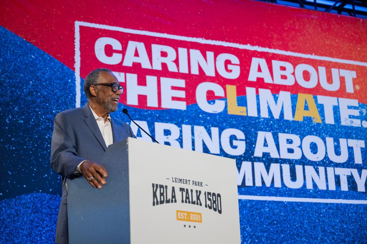 Person speaking behind a podium at the KBLA Talk 1580 Climate Change and Social Justice Symposium.