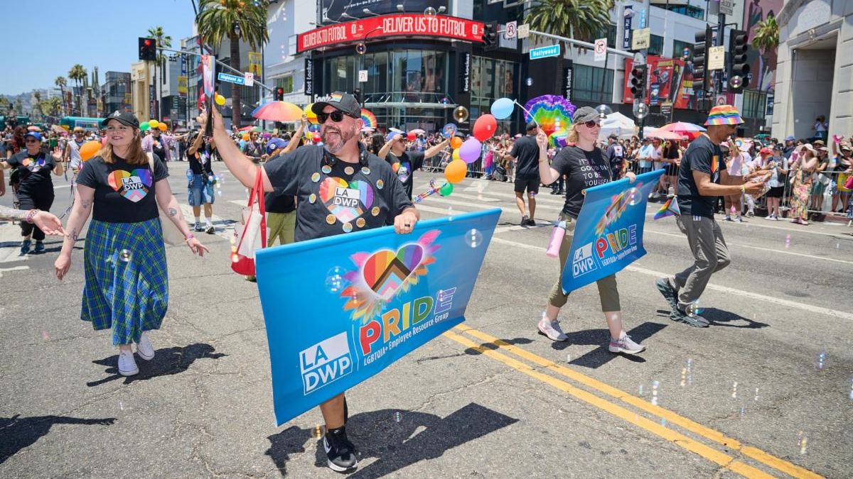 LADWP Pride Parade marchers wearing rainbow heart shirts carry LADWP Pride banners along Hollywood Blvd during the L.A. Pride Parade.