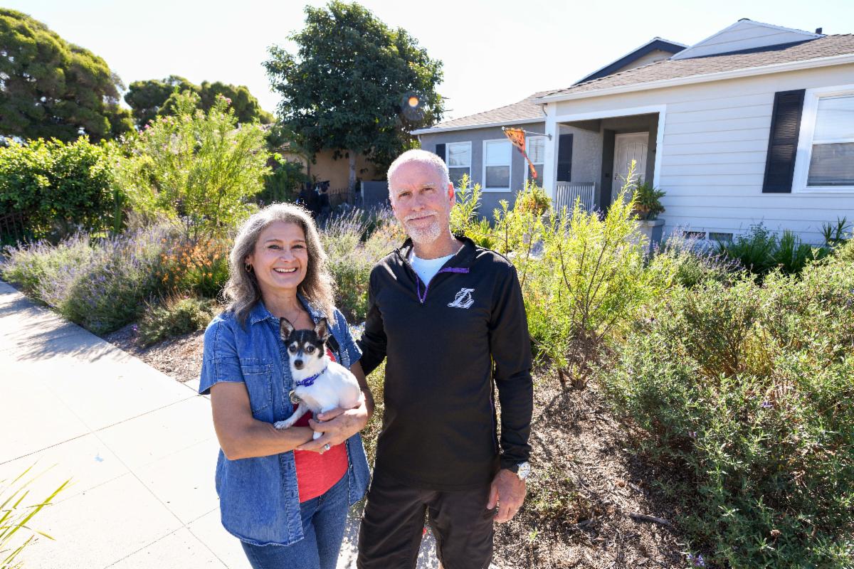 Customers standing in front of their drought tolerant landscaped front yard holding their dog