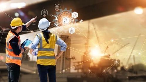 Two workers in safety vests and hard hats point while discussing a building. Graphics overlaid on the image show icons representing tools, interconnectivity, and workforce.
