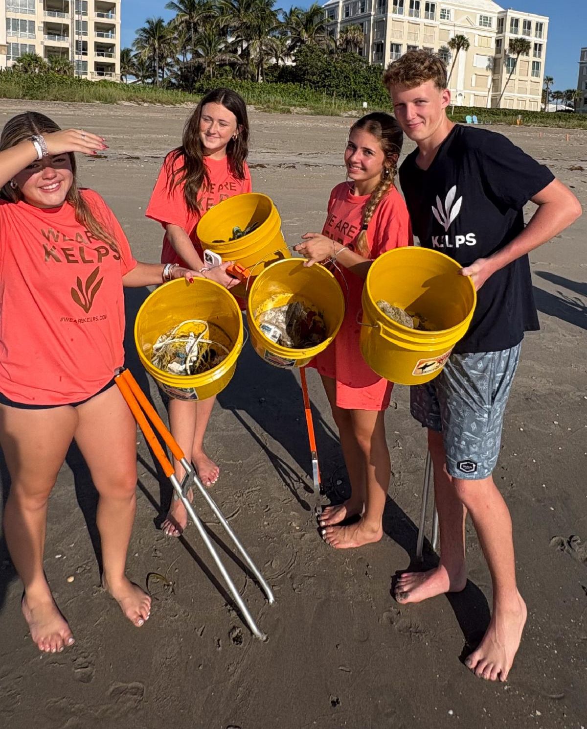 Group of people posing with buckets of beach debris