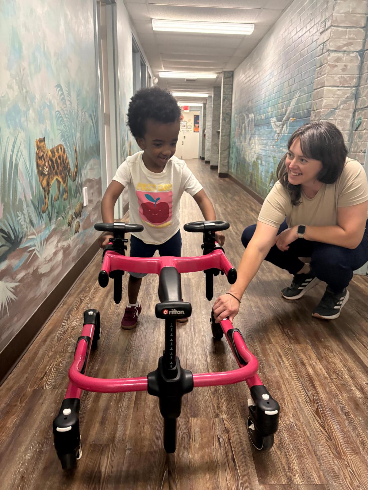 young child being assisted by his therapist, an older woman, teaching him how to maintain motor skills