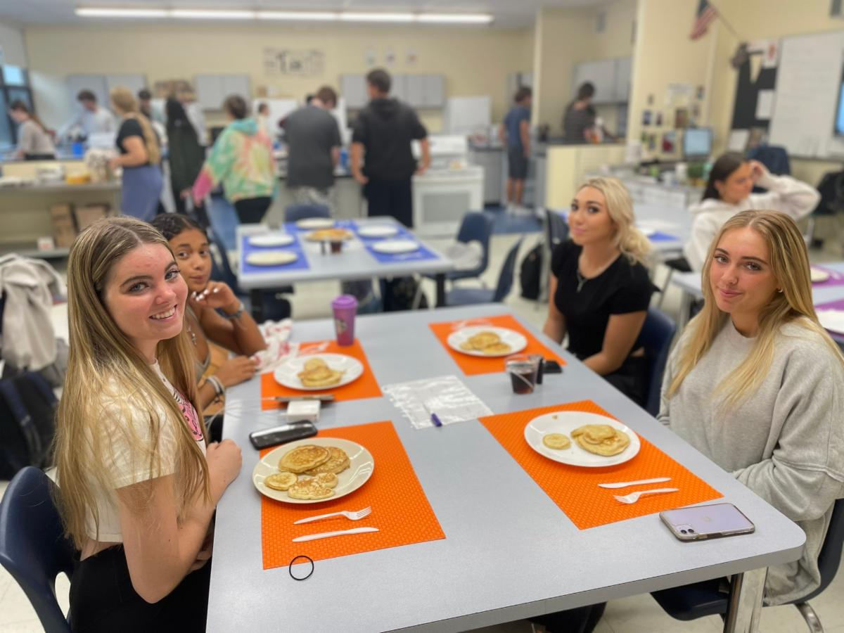 Four High School North culinary artists sit with a feast of freshly prepared pancakes before them.