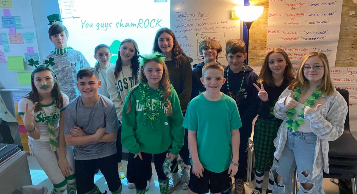 Middle school students wear green clothing, hats, glasses and necklaces in celebration of St. Patrick's Day.