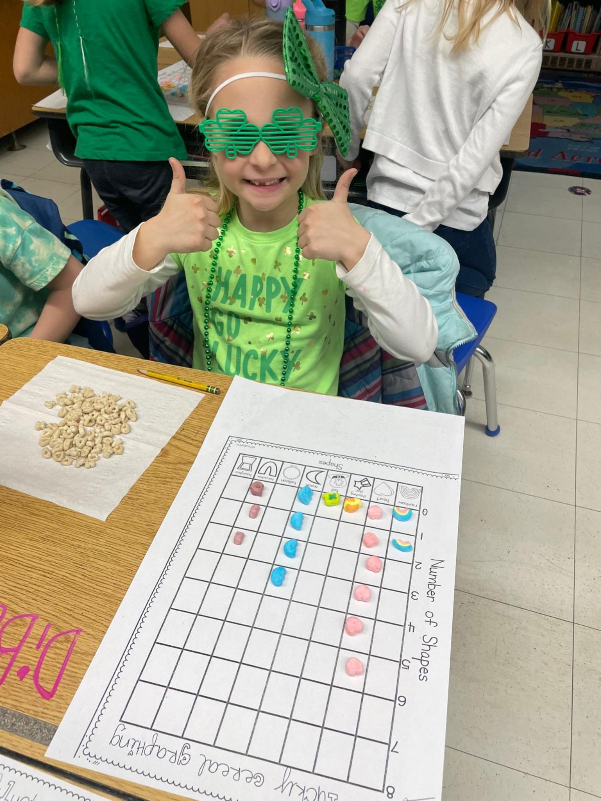 An elementary school students wears a green bow and shamrock shaped glasses in celebration of St. Patrick's Day.