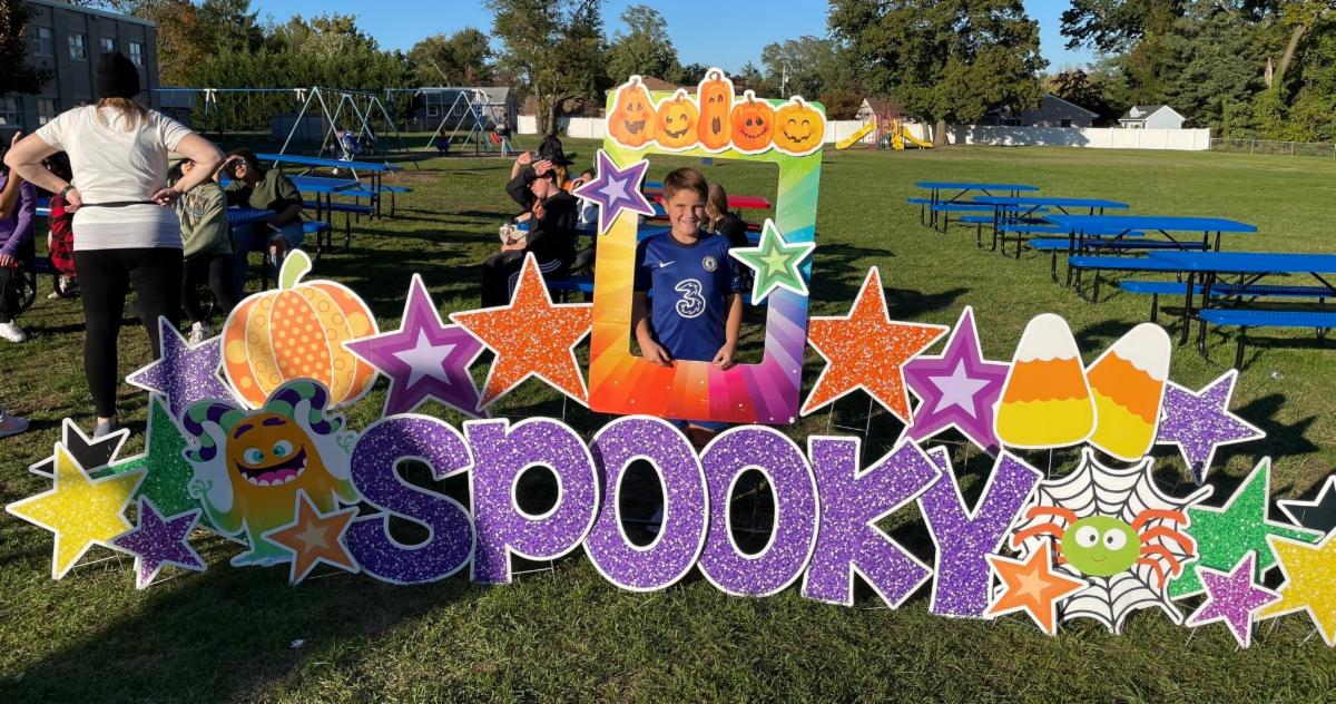 New Monmouth student stands in a giant picture frame next to a sign that says "spooky."