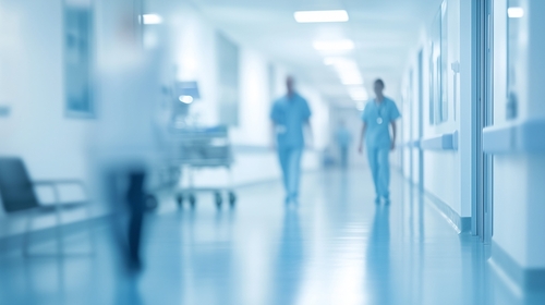 Blurred background of a hospital interior with medical equipment and people in motion_ a light blue color theme.