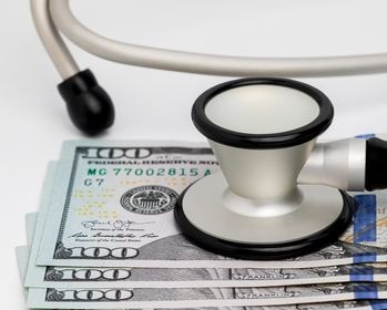 Blue medical phonendoscope and pack of dollars. The scene - health costs money