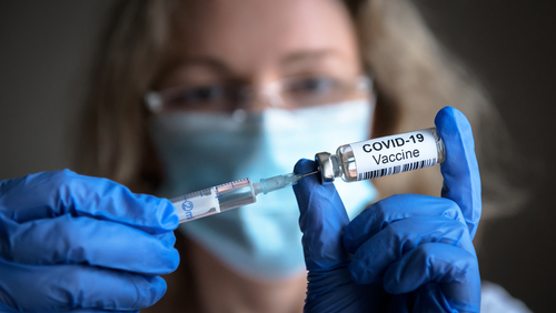 COVID-19 vaccine in researcher hands_ female doctor holds syringe and bottle with vaccine for coronavirus cure. Concept of corona virus treatment_ injection_ shot and clinical trial during pandemic.