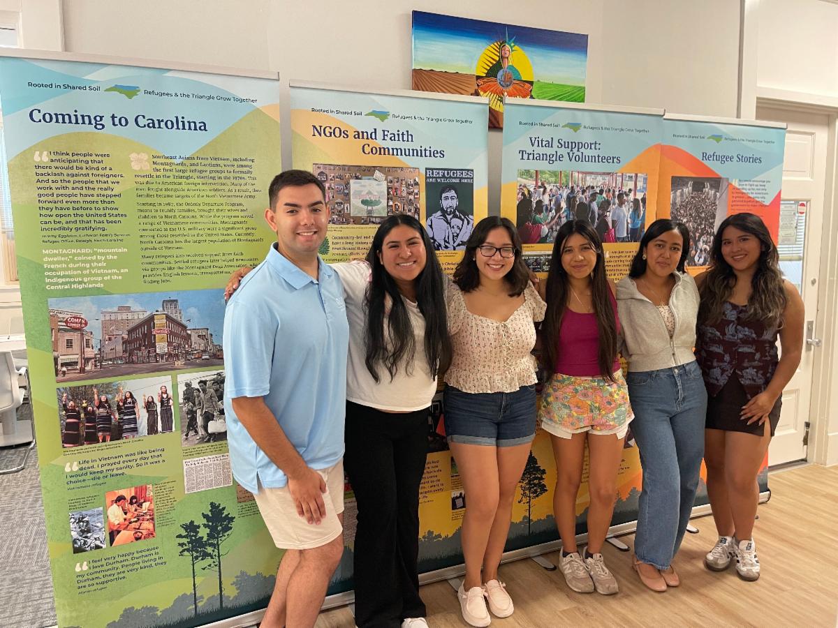 A group of six college students posing in front of four vertical educational banners 