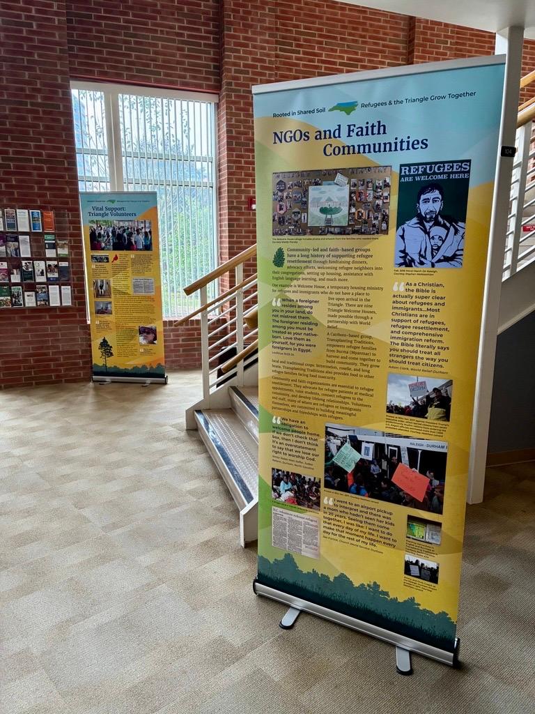 Two vertical banners with educational information about refugee resettlement displayed at the foot of stairs in a community center building