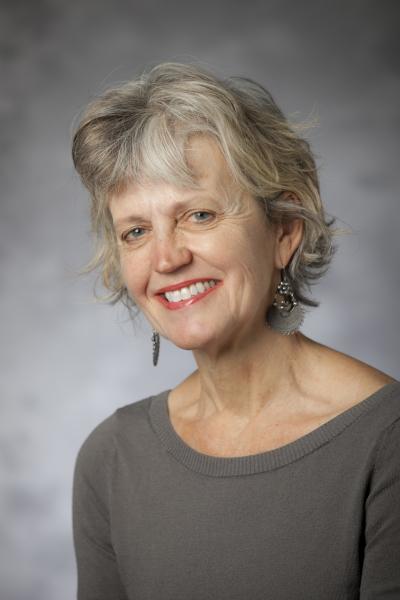 White woman with short grey hair smiling at the camera