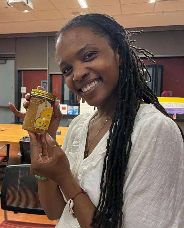 Amber Santibañez holding a jar of honey and smiling