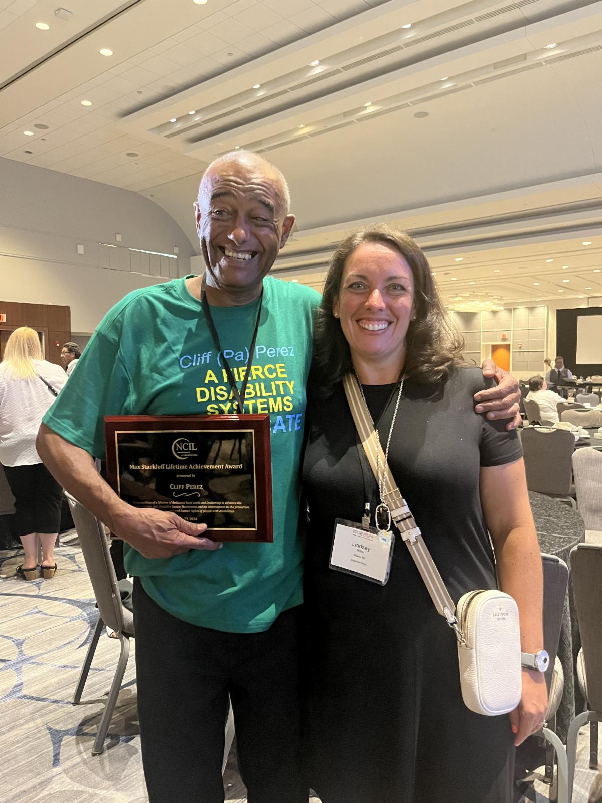 Image of Clif Perez holding his award standing to the left of NYAIL's executive director Lindsay Miller. Both with huge smiles
