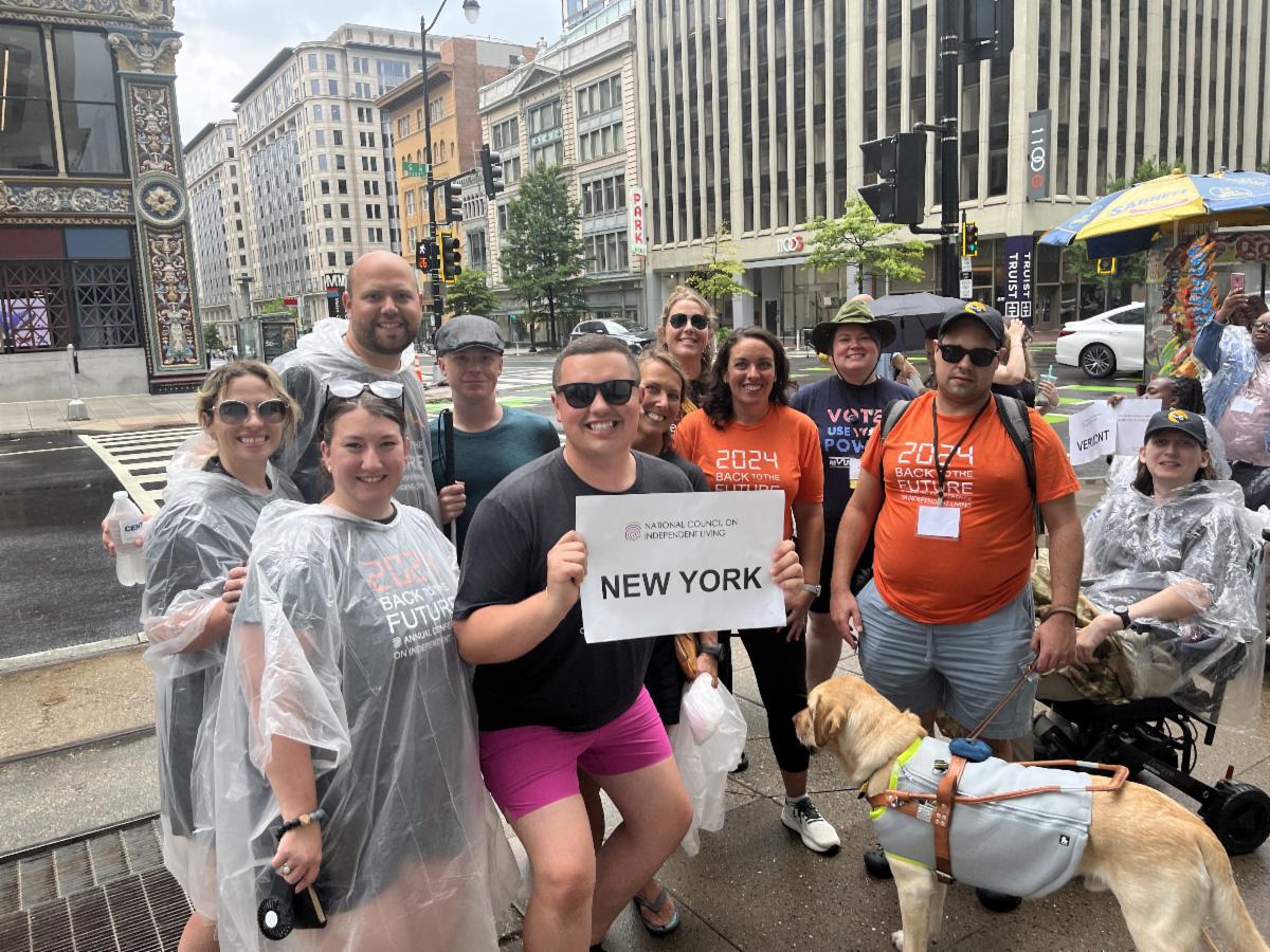 Group of advocates outside of the NCIL conference holding up a sign that says National Council on Independent Living New York