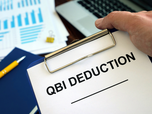 QBI Qualified Business Income Deduction documents in the hand.