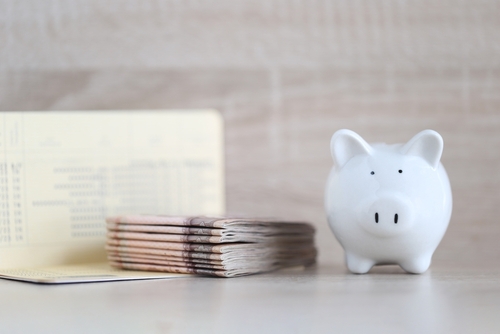 Piggy bank and banking account book on wooden background_ Save money for prepare in future and pension retirement concept