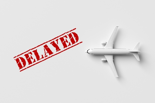 Flight delays. Toy airplane on a white background with a red delayed stamp next to it. 3d render.