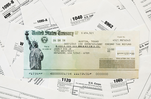 Refund check on many tax form blanks lies on table close up. Tax payers paperwork routine and bureaucracy concept