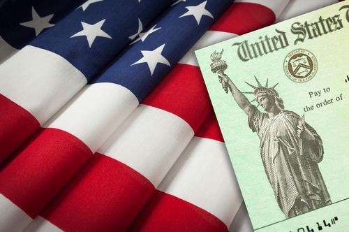 United States IRS Stimulus Check Resting on American Flag.