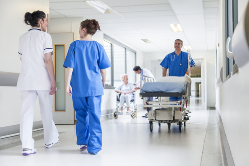 Male nurse pushing stretcher gurney bed in hospital corridor with doctor...