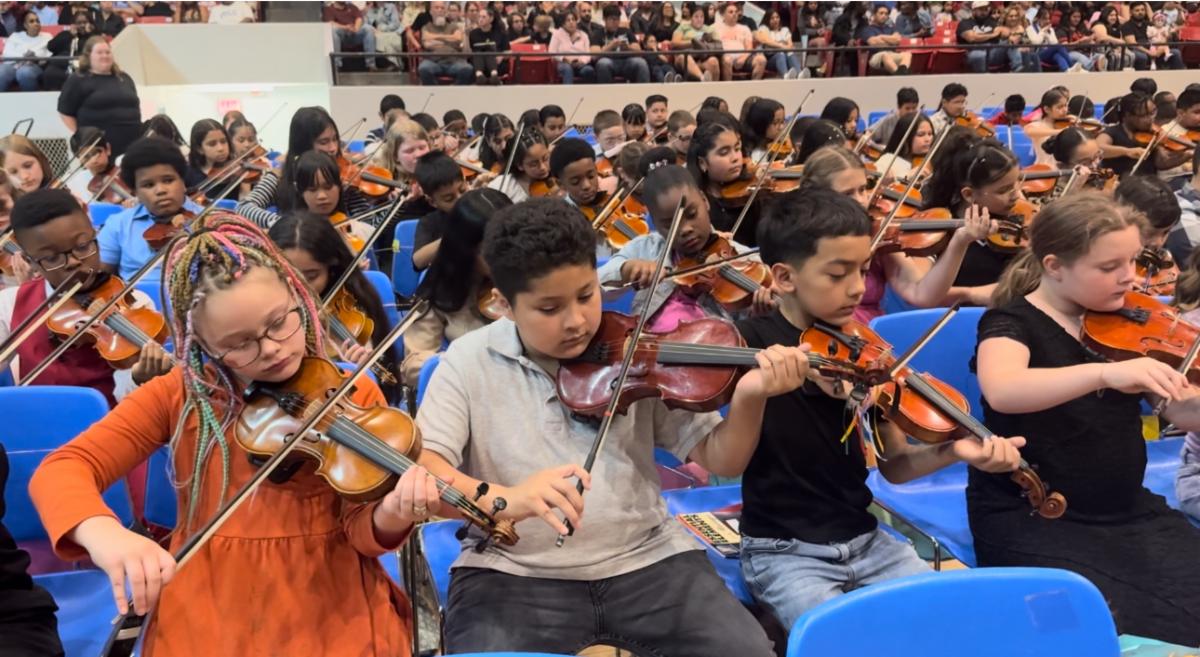Young elementary school students play the violin for the annual spring concert
