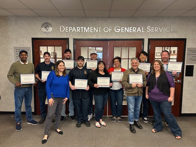 Instructors and participants smiling and standing with course completion certificates