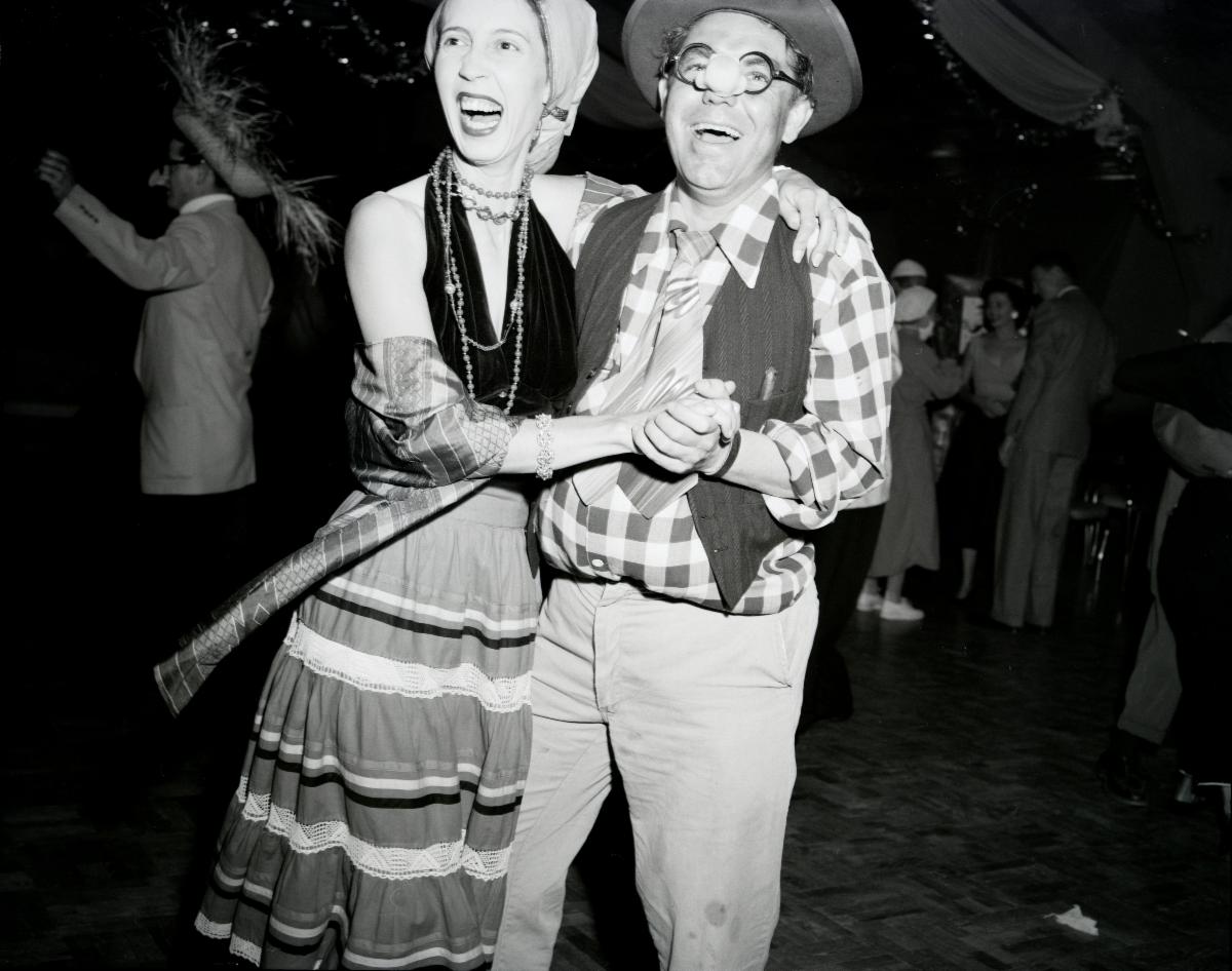 A man and woman dressed in costumes dance together at a party