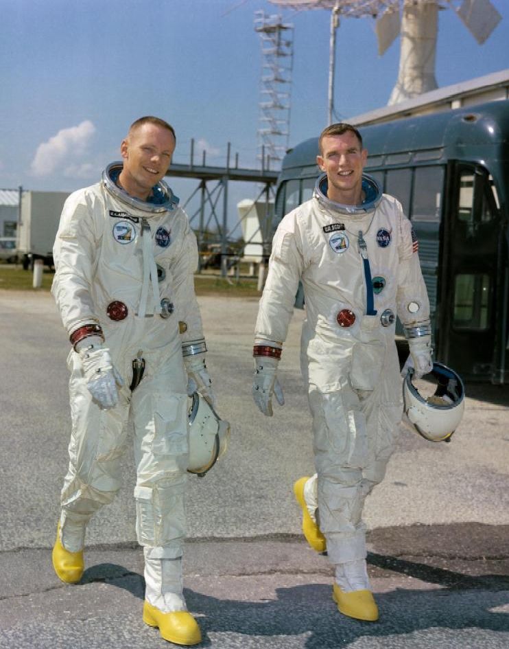 Astronauts Neil A. Armstrong (left), command pilot, and David R. Scott, pilot, the Gemini-8 prime crew, during a photo session outside the Kennedy Space Center Mission Control Center. Both men are wearing full spacesuits and carrying their helmets. 