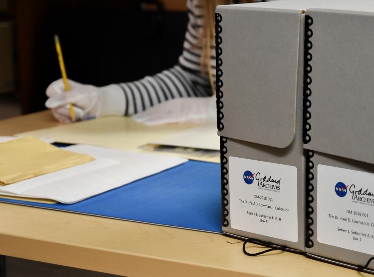 An archivist processes documents at a table at the Goddard archives