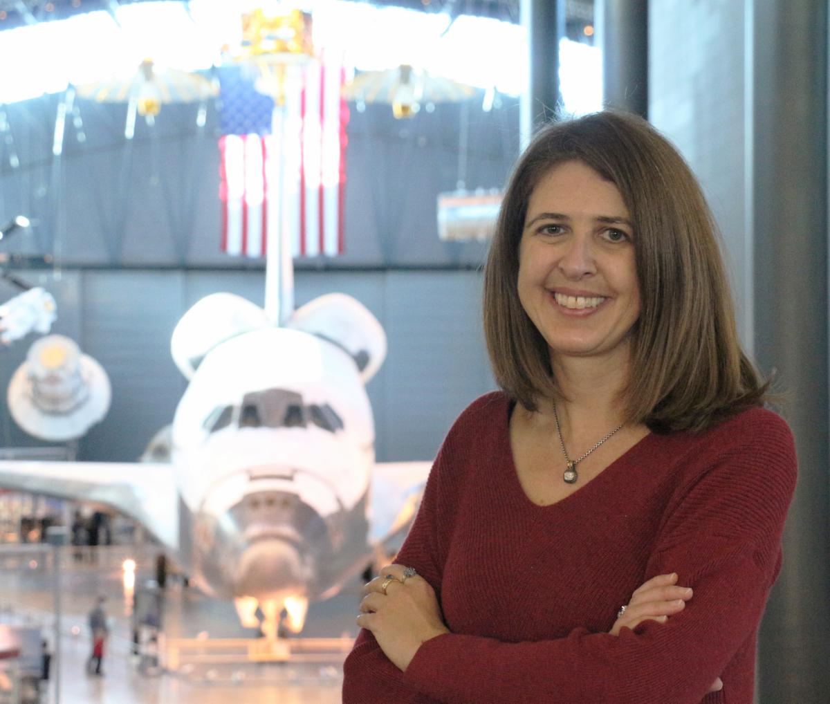 Dr. Amy Kaminski poses in front of Space Shuttle Discovery at the National Air and Space Museum's Udvar-Hazy Center.