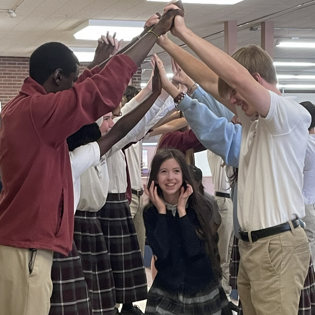 Fifth Grade Advancement - a fifth grade student passes through an arch of hands made by Upper School students