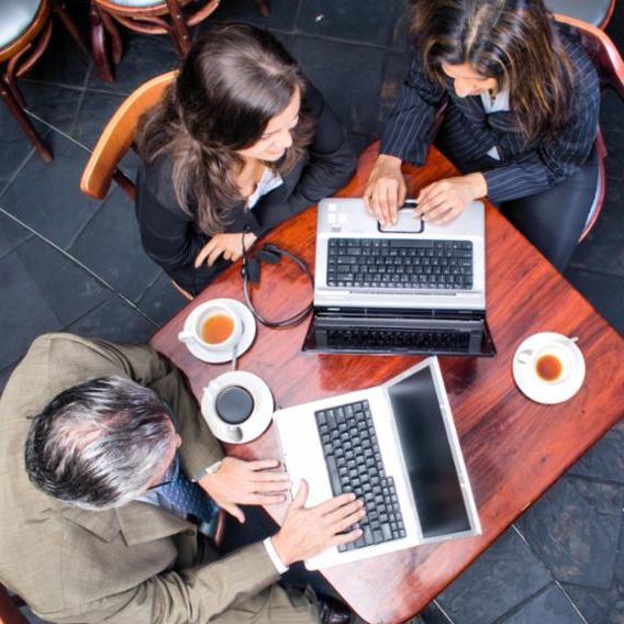 people meeting at a table with laptops