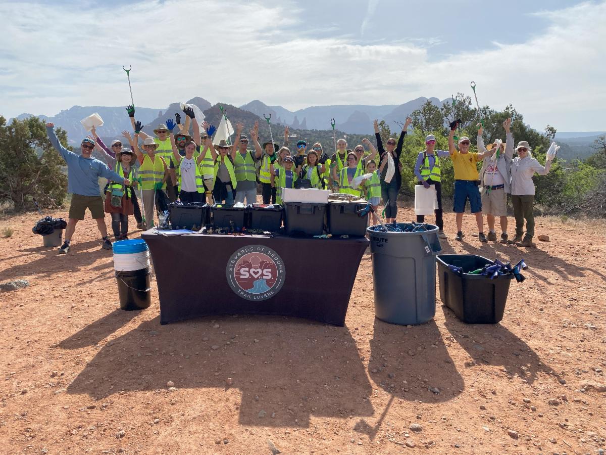 Group of Stewards of Sedona volunteers and staff jumping up for joy as they get ready for a clean up day in Red Rock Country.