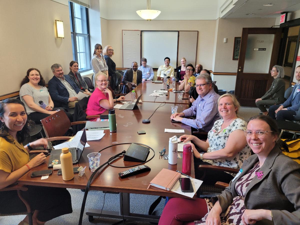 People gathered around a conference room table, smiling for the camera