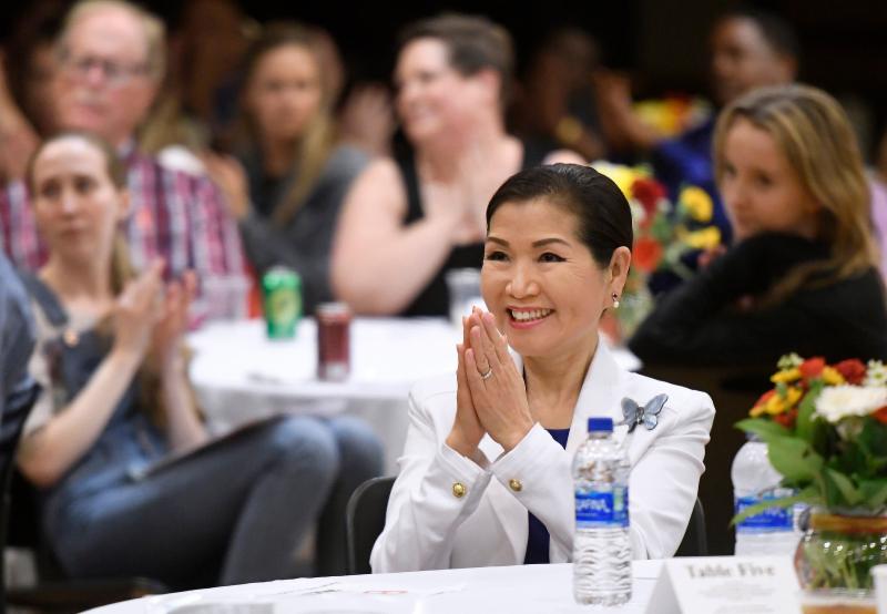 The First Lady sits at table smiling. 