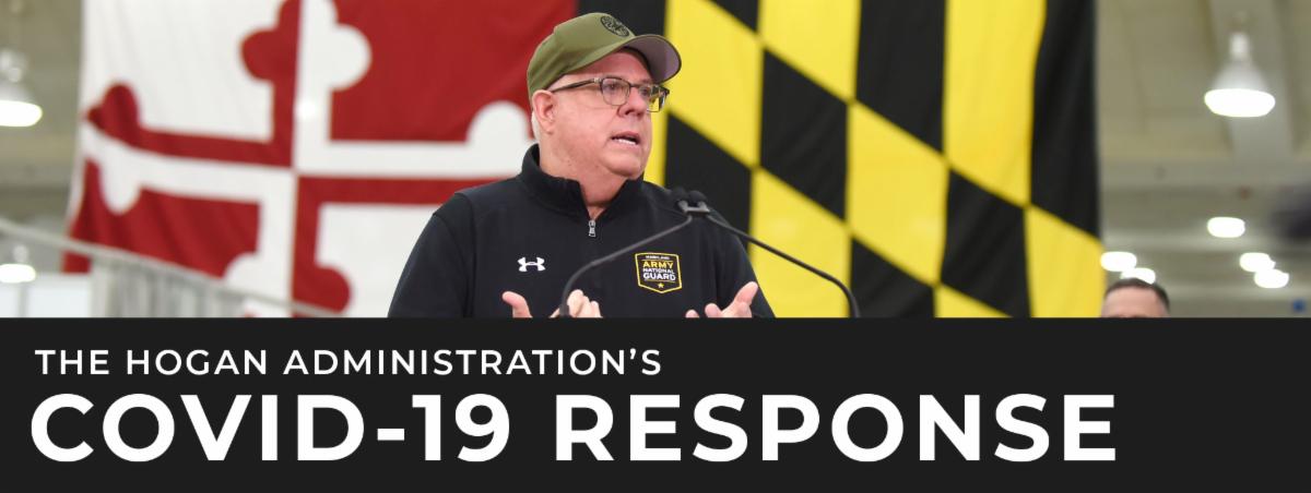 Governor stands in front of MD flag.  He_s wearing black pullover and khaki hat.