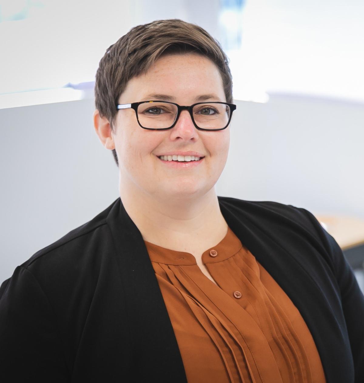 Headshot of Deputy Secretary Lisa Belcastro. White woman with short brown hair and glasses, wearing a brown shirt and black suit jacket. 