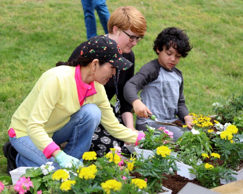 First Lady kneels in garden with student. 