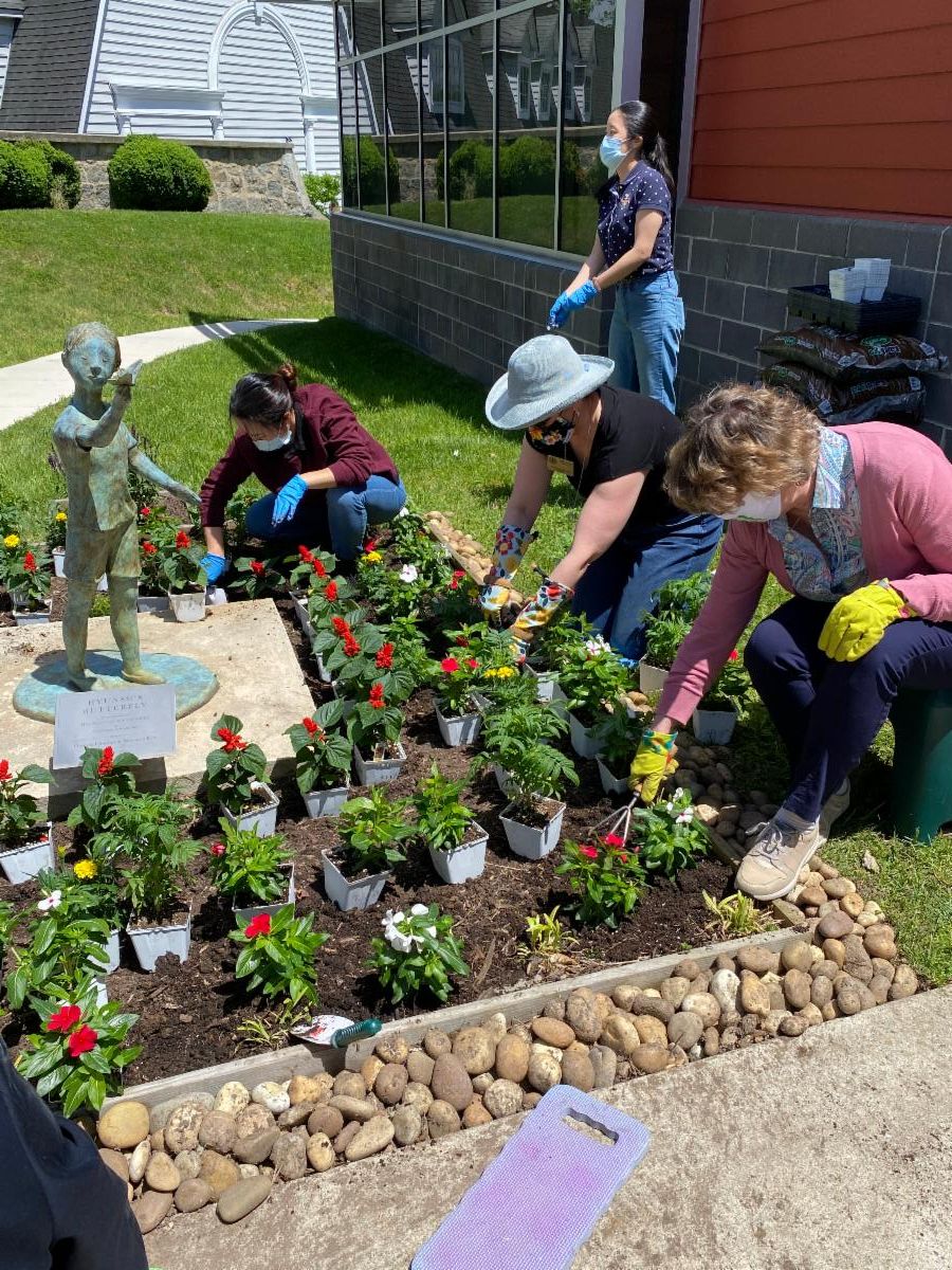 Secretary Beatty and Delegate Watson help plant flowers in bed with students. 