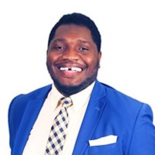 Headshot of man in blue suit_ white shirt and blue_white checked tie.