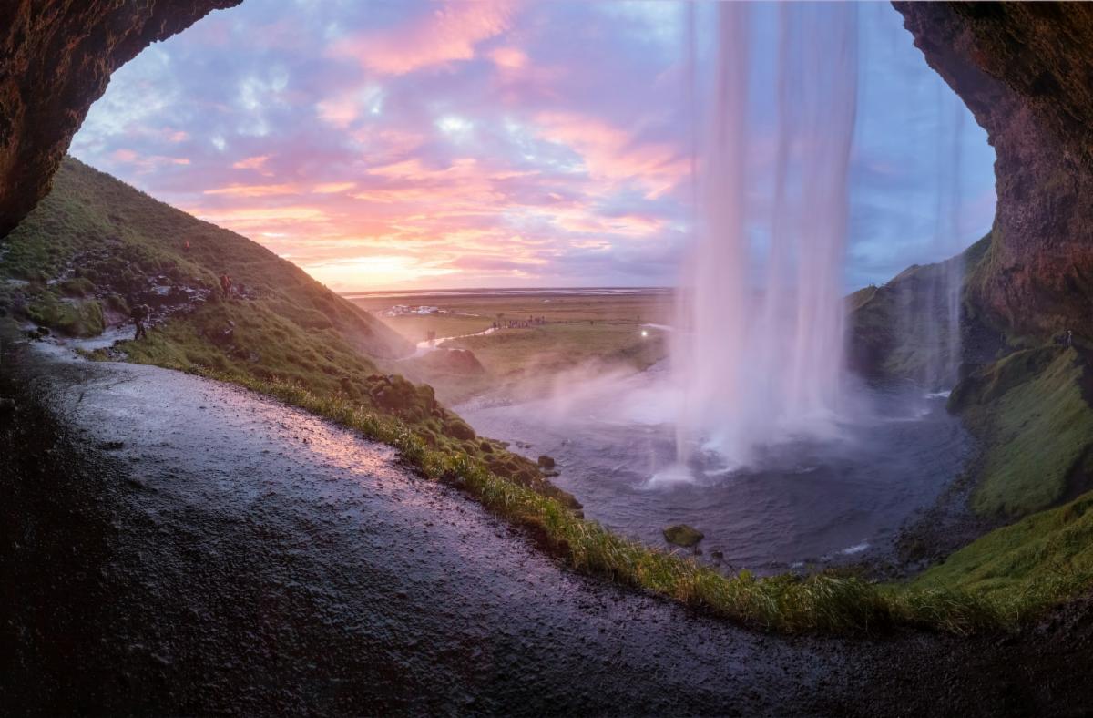 the view of a rosy sky from behind a waterfall in Iceland