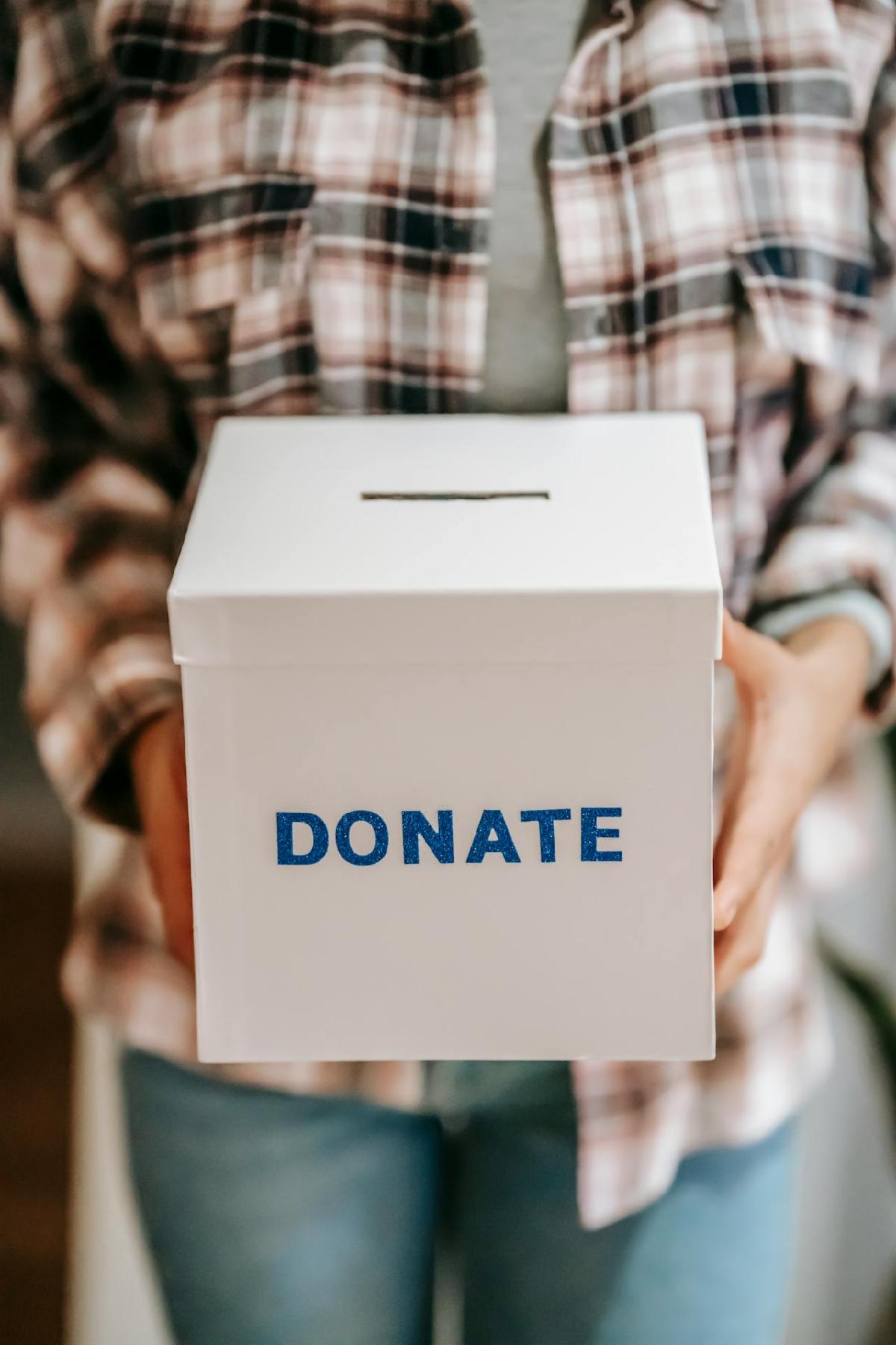 A person holding a white box labeled donate