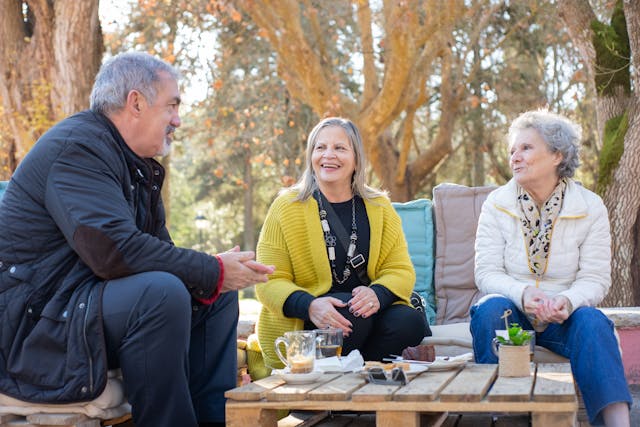 A trio of older adults around a table outside