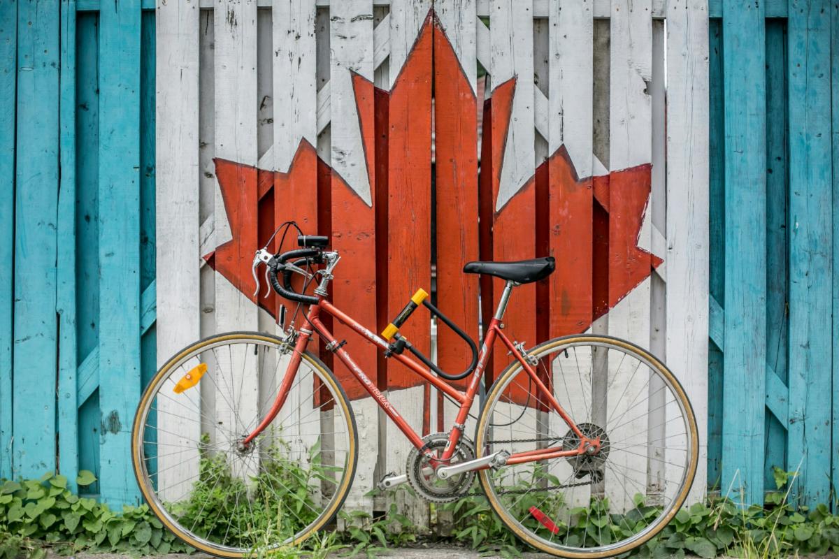 a bicycle in front of a fence painted with a maple leaf