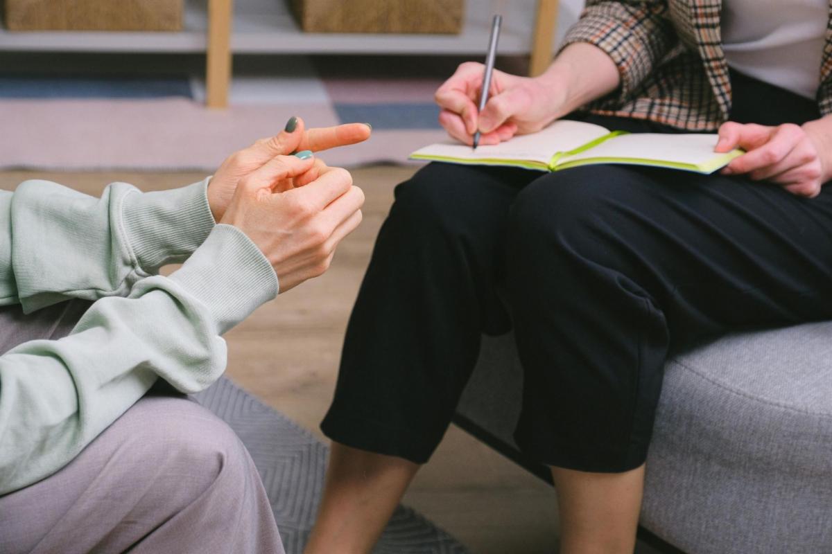 close-up of a person's hands while another person takes notes